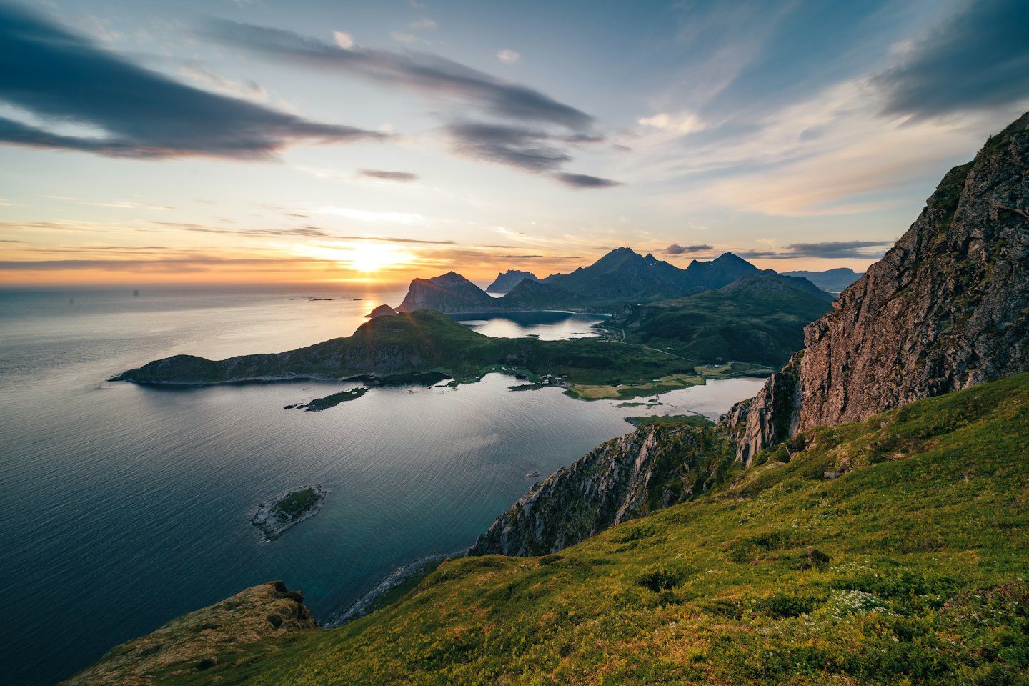Kustberg vid solnedgång med lugnt fjordvatten som reflekterar ljus.