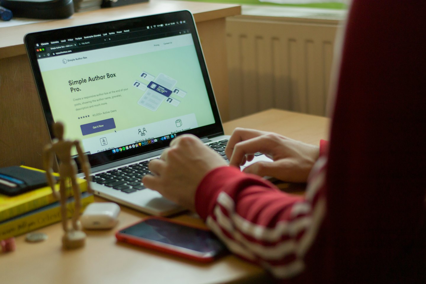 Person skriver på en laptop med webbplatsen 'Simple Author Box Pro' på skärmen.